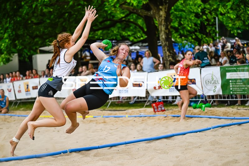 Spielerin (#12) beim Wurfversuch im Beach-Handball-Turnier