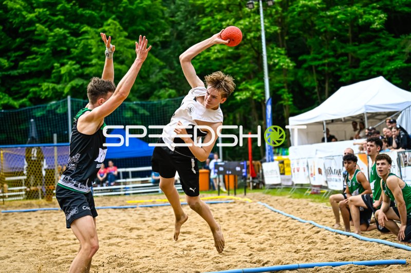 Wurfaktion beim Beach-Handball: Spieler springt gegen Abwehrblock