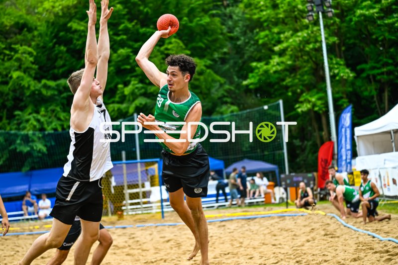 Wurf im Beach-Handball: Grüner Angreifer gegen weiß-schwarze Abwehr