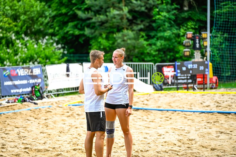 Zwei Beachvolleyball-Spieler im Gespräch auf dem Sandplatz