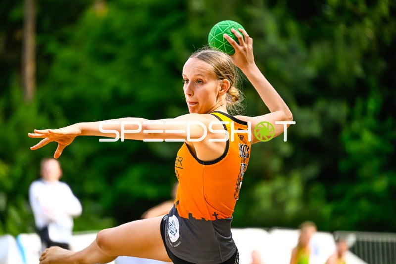 Spielerin im orangenen Trikot beim Wurfansatz im Beach-Handball