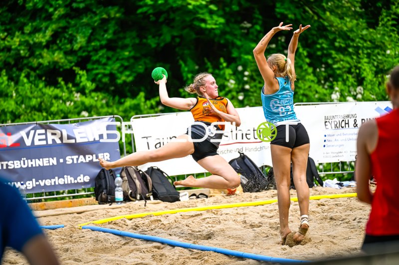 Wurfaktion beim Beach-Handball im Sprung gegen Abwehrspielerin