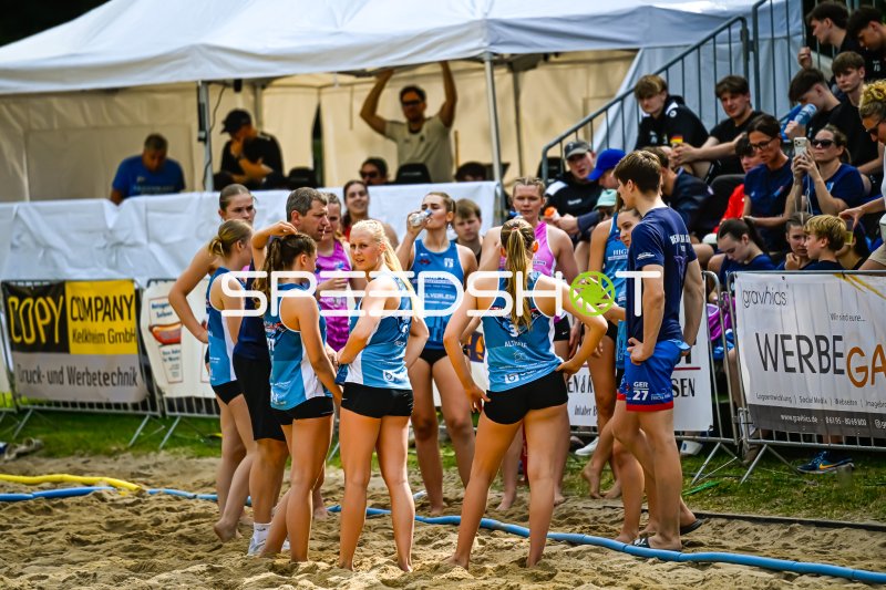 Beachhandball-Team in Auszeit-Besprechung am Sandfeld