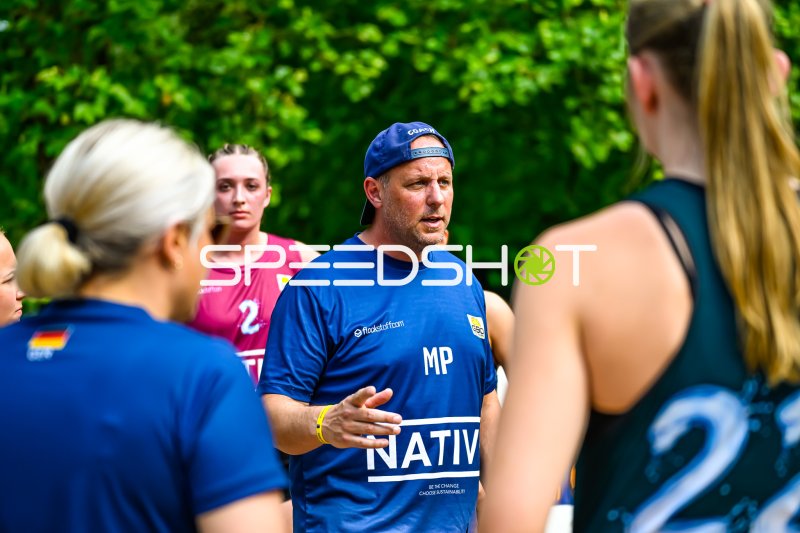 Trainer mit Initialen MP gibt Anweisungen an Spielerinnen