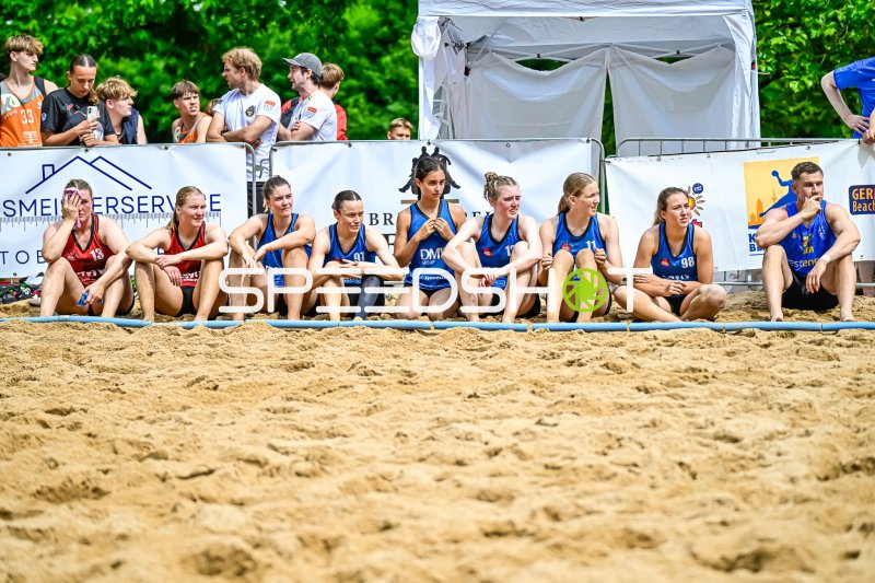 Spielerinnen verfolgen das Spiel am Rand des Beachhandball-Feldes