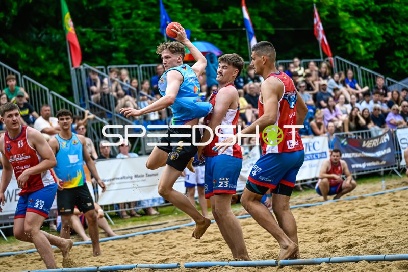 Wurfaktion im Beach-Handball: Spieler im Zweikampf gegen GER-Abwehr