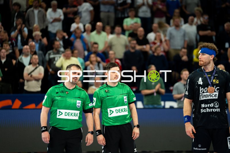 Johannes Golla (#3; SG Flensburg Handewitt) mit Medaille neben EHF-Schiedsrichtern