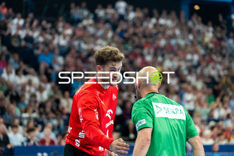 Spieler im roten Trikot diskutiert mit Schiedsrichter