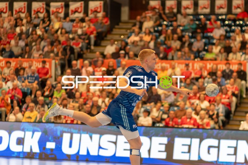 Spieler beim Sprungwurf in vollbesetzter Handball-Arena