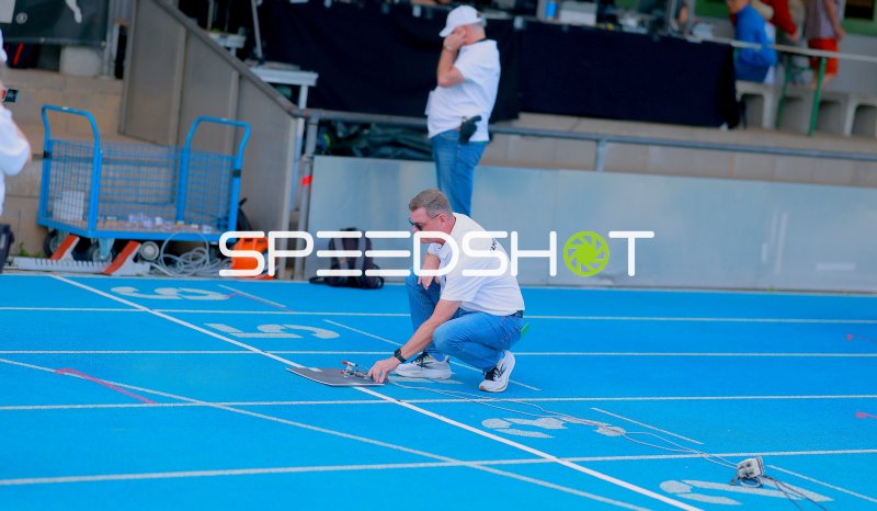 Kampfrichter bereitet Startblock auf der blauen Tartanbahn vor