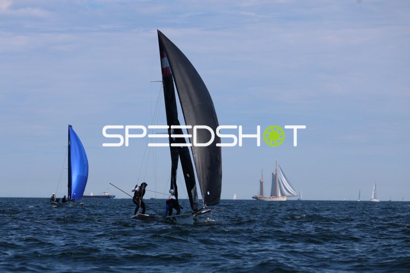 Segelboot mit schwarzem Spinnaker bei Regatta in Kiel