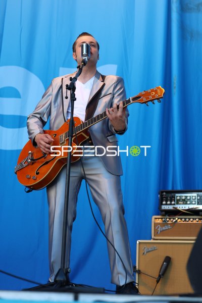 Musiker mit Gretsch-Gitarre und Vintage-Mikrofon bei Bühnenauftritt in Kiel