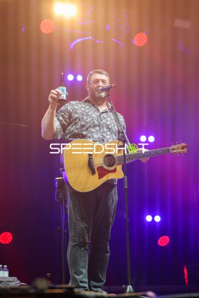 Musiker mit Akustikgitarre und Bierflasche auf der Bühne in Kiel